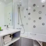 Salle de bain de la Chambre Familiale à l’hôtel Joyce avec un lavabo et une baignoire avec des visages sur les carreaux
