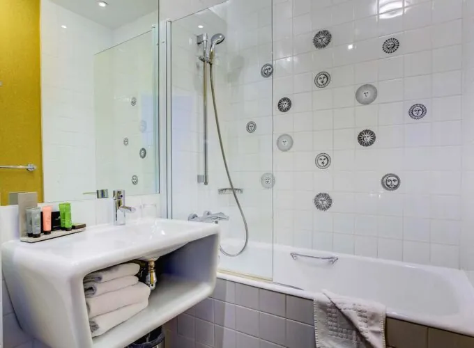 Salle de bain de la Chambre Familiale à l’hôtel Joyce avec un lavabo et une baignoire avec des visages sur les carreaux