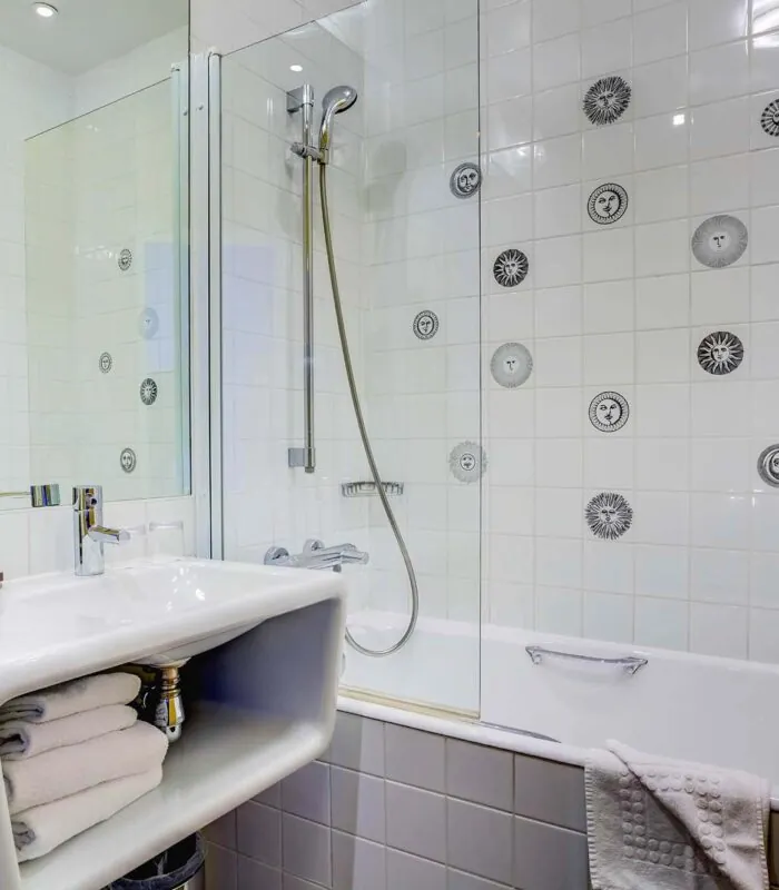 Salle de bain de la Chambre Familiale à l’hôtel Joyce avec un lavabo et une baignoire avec des visages sur les carreaux