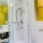 Salle de bain de la Chambre Familiale à l’hôtel Joyce avec des carreaux blancs et un mur jaune