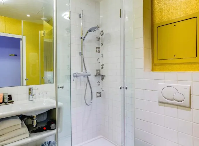 Salle de bain de la Chambre Familiale à l’hôtel Joyce avec des carreaux blancs et un mur jaune