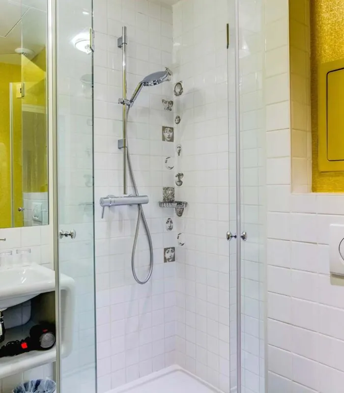 Salle de bain de la Chambre Familiale à l’hôtel Joyce avec des carreaux blancs et un mur jaune