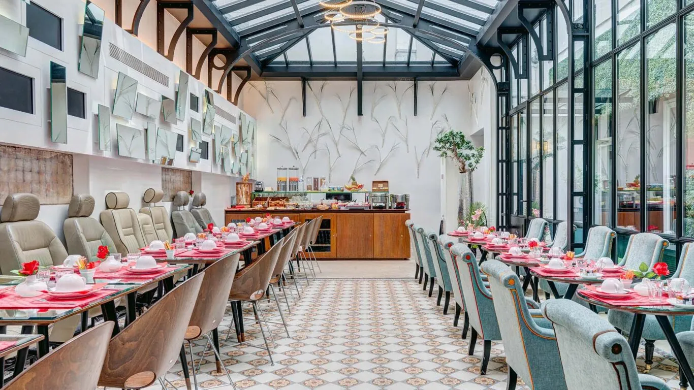 Salle de petit-déjeuner de l’hôtel Joyce 3 étoiles du groupe Astotel à Paris, située sous une verrière avec une décoration originale et un buffet à l’arrière