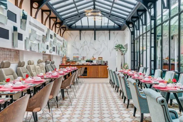 Salle de petit-déjeuner de l’hôtel Joyce 3 étoiles du groupe Astotel à Paris, située sous une verrière avec une décoration originale et un buffet à l’arrière