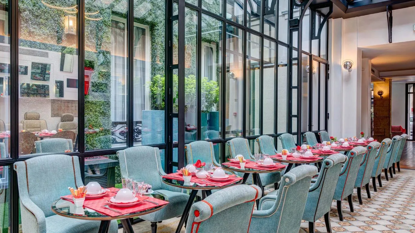 Salle de petit-déjeuner de l’hôtel Joyce 3 étoiles du groupe Astotel à Paris, située sous une verrière avec une décoration originale et un buffet à l’arrière