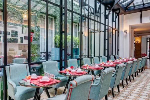 Salle de petit-déjeuner de l’hôtel Joyce 3 étoiles du groupe Astotel à Paris, située sous une verrière avec une décoration originale et un buffet à l’arrière