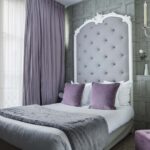 Un lit avec des oreillers violets et une tête de lit blanche à l’Hôtel Le 123 Sébastopol
