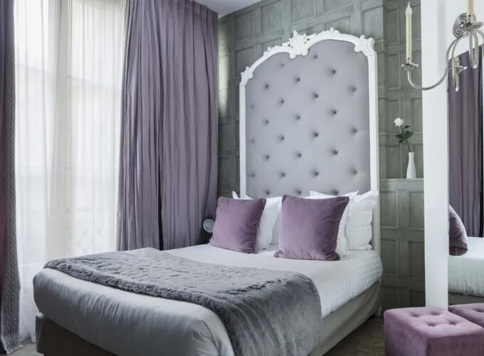 Un lit avec des oreillers violets et une tête de lit blanche à l’Hôtel Le 123 Sébastopol