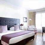 Chambre Double Privilège à l’hôtel Le 123 Elysées avec un grand lit et des oreillers violets