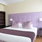 Chambre Double Supérieure à l’hôtel Le 123 Elysées avec une tête de lit violette et des oreillers violets