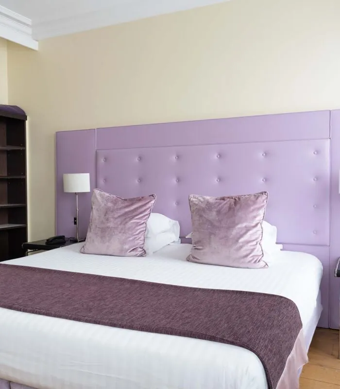Chambre Double Supérieure à l’hôtel Le 123 Elysées avec une tête de lit violette et des oreillers violets
