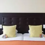 Chambre Familiale à l’hôtel Le 123 Elysées avec une tête de lit noire et des oreillers jaunes