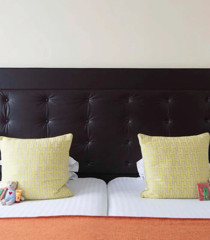 Chambre Familiale à l’hôtel Le 123 Elysées avec une tête de lit noire et des oreillers jaunes