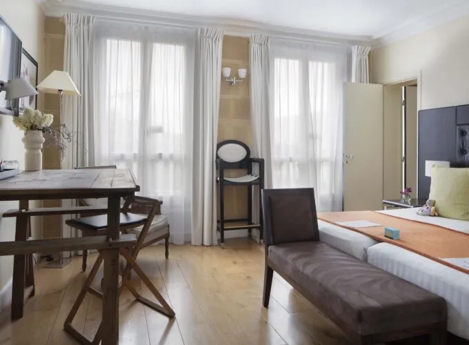 Chambre Familiale à l’hôtel Le 123 Elysées avec deux lits, un bureau et un banc