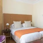 Chambre Familiale à l’hôtel Le 123 Elysées avec deux lits et une chaise violette