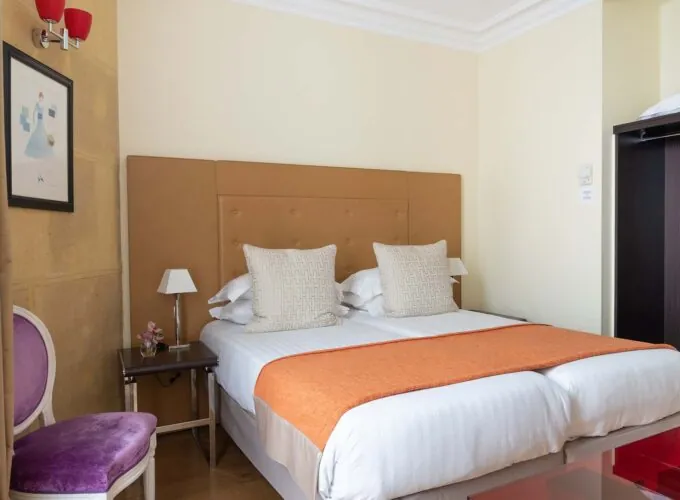 Chambre Familiale à l’hôtel Le 123 Elysées avec deux lits et une chaise violette