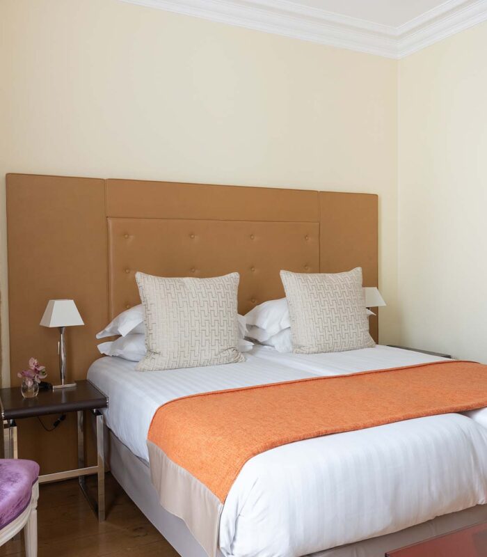 Chambre Familiale à l’hôtel Le 123 Elysées avec deux lits et une chaise violette