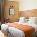 Chambre Familiale à l’hôtel Le 123 Elysées avec deux lits et une chaise violette