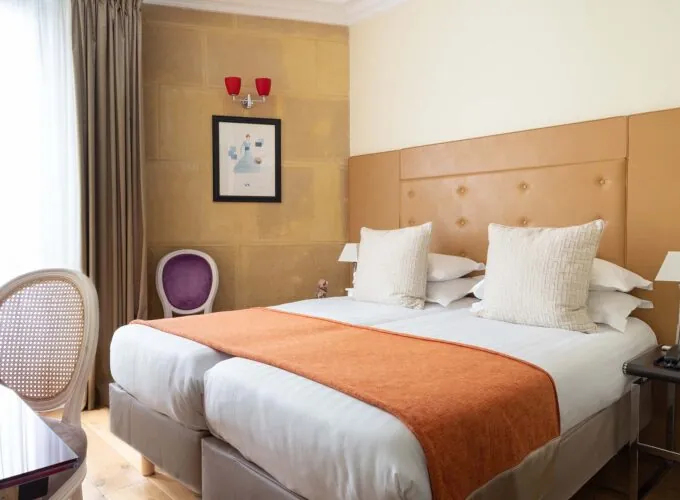 Chambre Familiale à l’hôtel Le 123 Elysées avec deux lits et une chaise violette