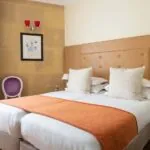 Chambre Familiale à l’hôtel Le 123 Elysées avec deux lits et une chaise violette