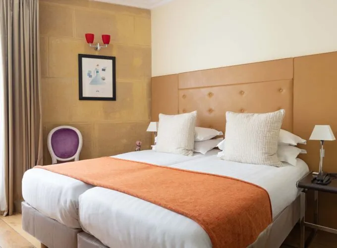 Chambre Familiale à l’hôtel Le 123 Elysées avec deux lits et une chaise violette