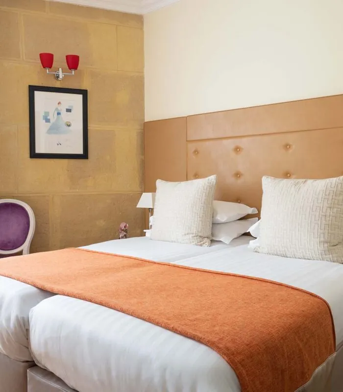 Chambre Familiale à l’hôtel Le 123 Elysées avec deux lits et une chaise violette