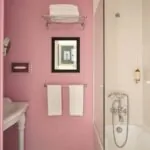 Salle de bain de la Chambre Familiale à l’hôtel Le 123 Elysées avec des murs roses et une baignoire