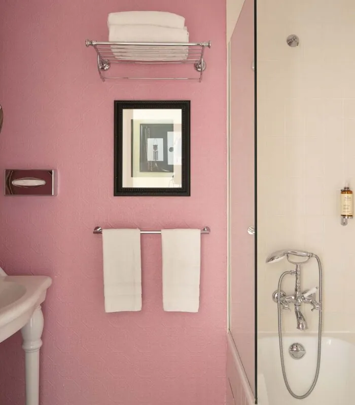 Salle de bain de la Chambre Familiale à l’hôtel Le 123 Elysées avec des murs roses et une baignoire