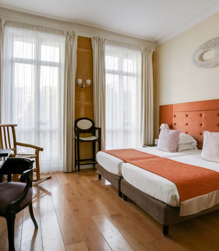 Chambre pour personnes à mobilité réduite à l’hôtel Le 123 Elysées avec deux lits, un bureau et une chaise