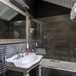 Salle de bain mansardée d'une chambre Double à l’Hôtel Le 123 Elysées avec du carrelage gris anthracite, un miroir, un lavabo et une baignoire