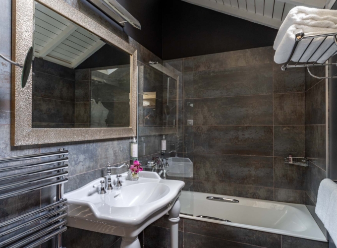 Salle de bain mansardée d'une chambre Double à l’Hôtel Le 123 Elysées avec du carrelage gris anthracite, un miroir, un lavabo et une baignoire