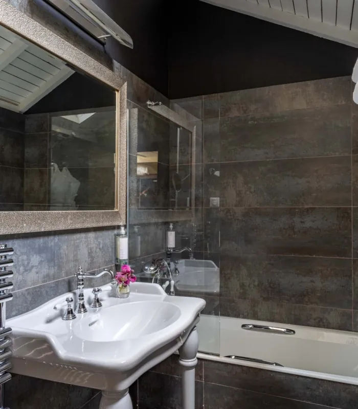 Salle de bain mansardée d'une chambre Double à l’Hôtel Le 123 Elysées avec du carrelage gris anthracite, un miroir, un lavabo et une baignoire