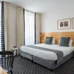 Chambre Double Supérieure avec un grand lit et une chaise à l’Hôtel Lorette