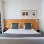 Chambre Double Supérieure avec un lit et deux tableaux au mur à l’Hôtel Lorette