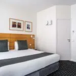 Chambre Double Supérieure avec un lit et trois tableaux au mur à l’Hôtel Lorette