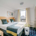 Chambre Familiale avec deux lits et une télévision à écran plat à l’Hôtel Lorette