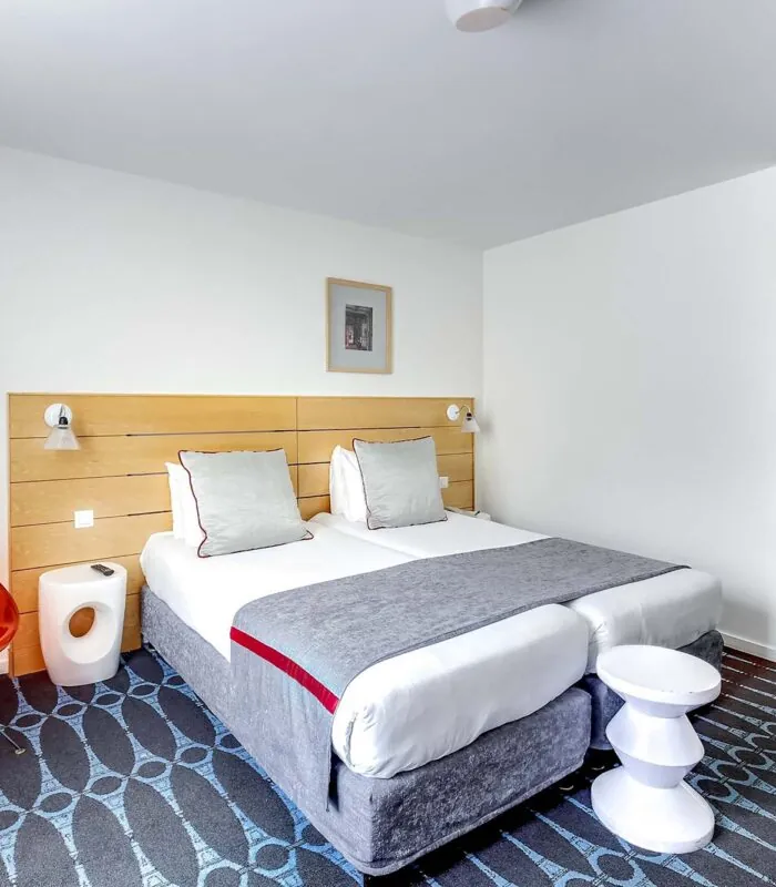 Chambre Familiale Supérieure avec deux lits et une chaise rouge à l’Hôtel Lorette