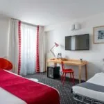 Chambre Privilège avec un lit, un bureau et une télévision à écran plat à l’Hôtel Lorette