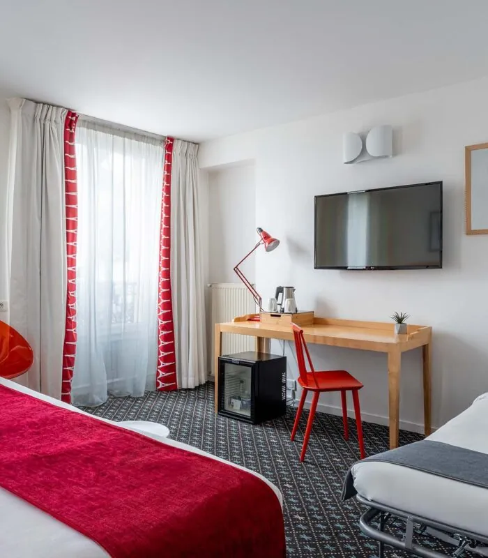 Chambre Privilège avec un lit, un bureau et une télévision à écran plat à l’Hôtel Lorette