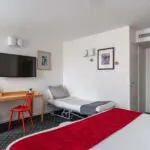 Chambre Privilège avec un lit, un bureau et une télévision à écran plat à l’Hôtel Lorette