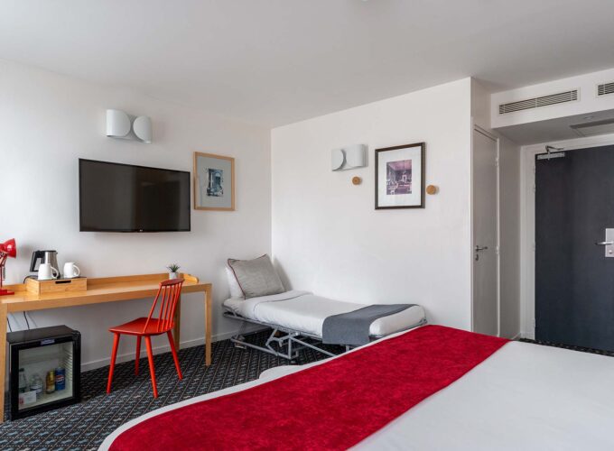 Chambre Privilège avec un lit, un bureau et une télévision à écran plat à l’Hôtel Lorette