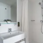 Salle de bain d’une Chambre Single avec un lavabo, un miroir et une douche à l’Hôtel Lorette