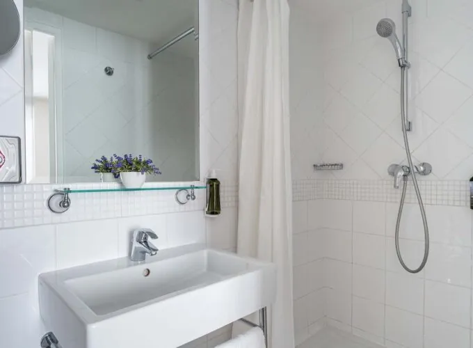 Salle de bain d’une Chambre Twin avec un lavabo, un miroir et une douche à l’Hôtel Lorette