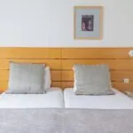 Lit d’une Chambre Twin Supérieure avec deux oreillers et un tableau au mur au-dessus du lit à l’Hôtel Lorette