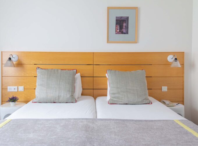 Lit d’une Chambre Twin Supérieure avec deux oreillers et un tableau au mur au-dessus du lit à l’Hôtel Lorette