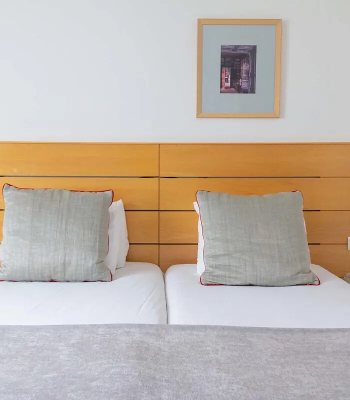 Lit d’une Chambre Twin Supérieure avec deux oreillers et un tableau au mur au-dessus du lit à l’Hôtel Lorette