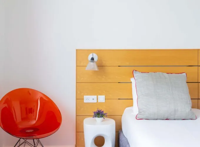 Chambre Twin Supérieure avec une chaise orange et une table blanche à l’Hôtel Lorette