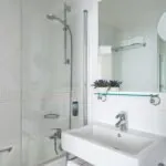 Salle de bain d’une Chambre Twin Supérieure avec un lavabo, un miroir et une douche à l’Hôtel Lorette
