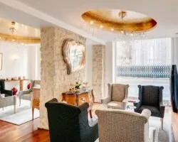 Vue du lobby de l’Hôtel 3 étoiles Lorette à Paris, où l’élégance des couleurs se marie harmonieusement avec le charme des murs en pierre historiques, créant une atmosphère raffinée