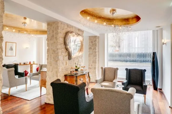 Vue du lobby de l’Hôtel 3 étoiles Lorette à Paris, où l’élégance des couleurs se marie harmonieusement avec le charme des murs en pierre historiques, créant une atmosphère raffinée